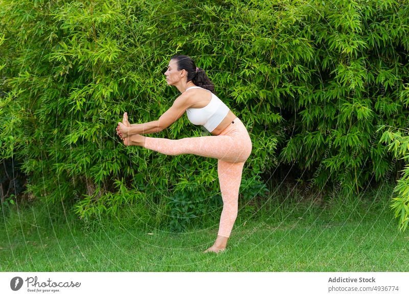Frau macht Stehende Hand zum großen Zeh Asana im Park Training stehende Hand bis zum großen Zeh Yoga Übung üben Gleichgewicht Rasen Zen Sportbekleidung Hobby