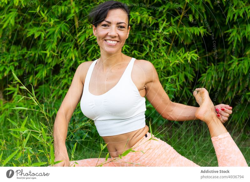 Lächelnde Frau beim Asana im Park Yoga Training Übung üben Hobby Gesunder Lebensstil anstrengen positiv froh Optimist Baum Inhalt heiter Sportbekleidung