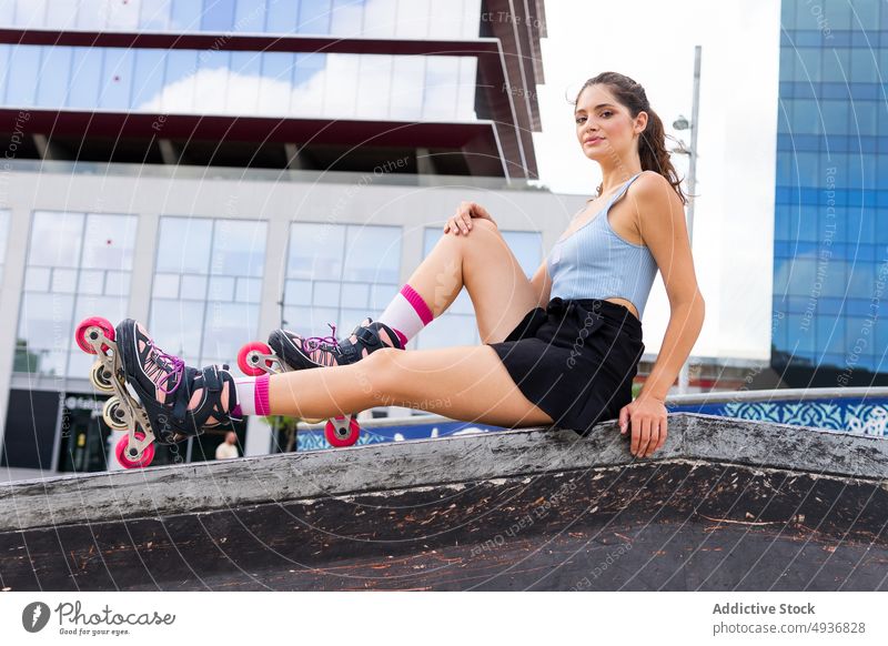 Fitte junge Frau mit Rollschuhen ruht sich nach dem Training im Skatepark aus Rollerblade Skateplatz Großstadt Aktivität selbstsicher Sommer Hobby cool