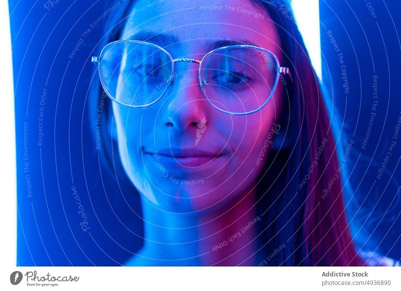 Junge Frau auf dem Flur eines Nachtclubs Gang Wand blau neonfarbig futuristisch leuchten farbenfroh jung lange Haare hell Brille glühen modern Nachtleben