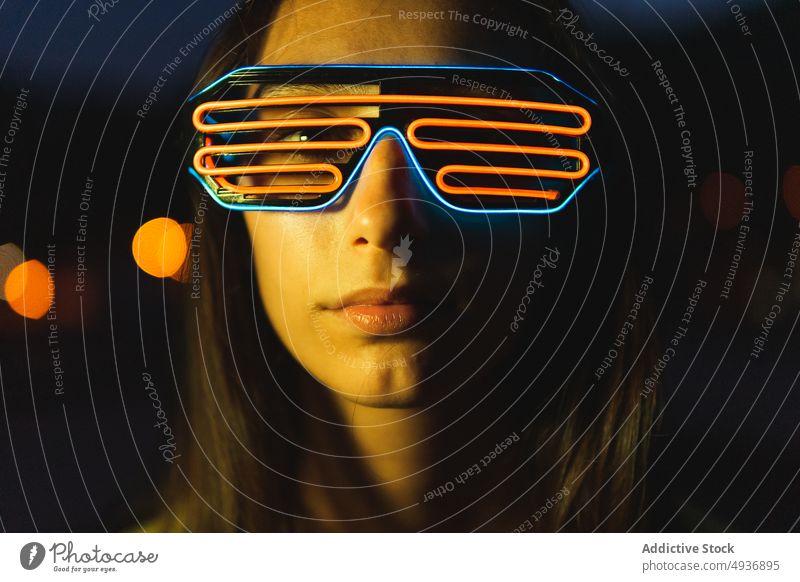 Junge Frau mit futuristischer Brille bei Nacht dunkel Stil Vorschein neonfarbig Porträt Cyberpunk dunkles Haar jung Persönlichkeit Menschliches Gesicht