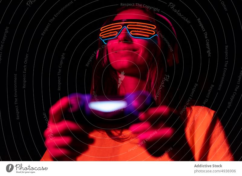 Futuristischer junger Gamer beim Spielen in der Nacht Frau Spieler Videospiel spielen futuristisch spät Gamepad Lächeln Rotlicht modern Gerät Apparatur