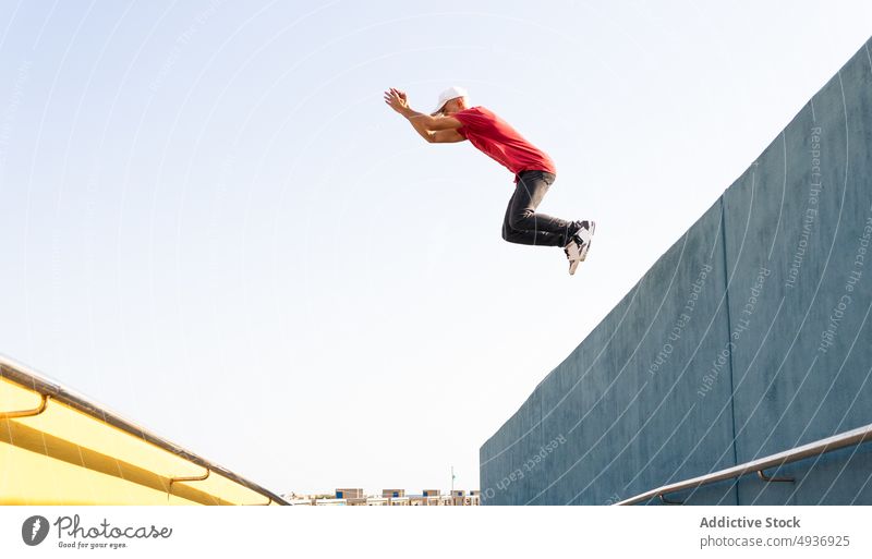 Energetischer Mann, der von einem Gebäude springt und einen Parkour-Stunt zeigt Le Parkour Trick springen Saum Energie Hipster Großstadt männlich extrem urban