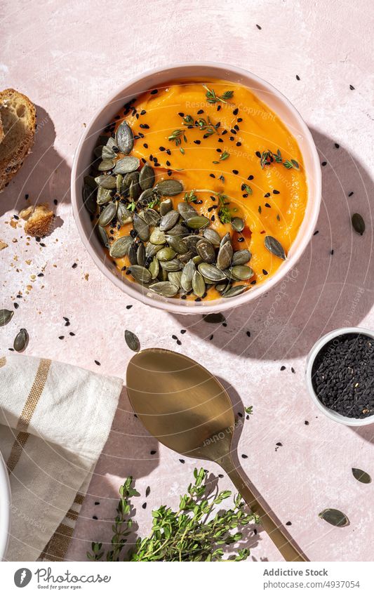 Schüssel mit gesunder Kürbiscremesuppe, die auf dem Tisch neben Brotscheiben serviert wird Suppe Samen gesunde Ernährung selbstgemacht Lebensmittel Püree