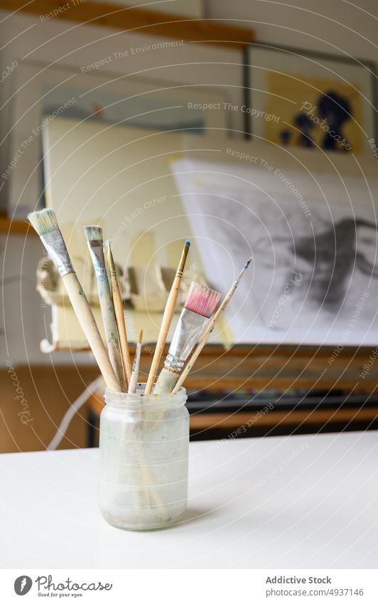 Gefäß mit Pinseln auf Staffelei Glas Pinselblume Papier Werkstatt Kunst blanko kreativ Handwerk Hobby dreckig Kulisse Inspiration Vorrat Schot Arbeitsplatz
