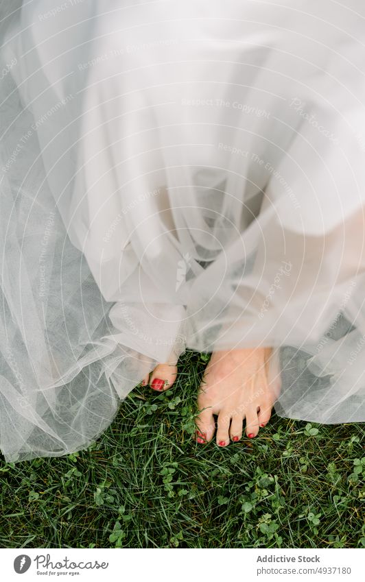Crop anonyme Braut im Hochzeitskleid auf Rasen stehen Frau romantisch feiern Heirat Anlass hochzeitlich Jungvermählter Wiese Natur Barfuß Veranstaltung Stil