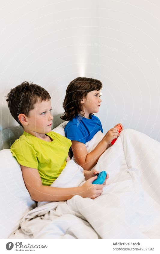 Kinder spielen ein Videospiel im Bett Geschwisterkind Gamepad unterhalten Vergnügen Zeitvertreib Freizeit Hobby fokussiert Schwester konzentriert Bruder Junge