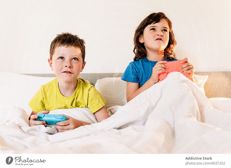 Kinder spielen ein Videospiel im Bett Geschwisterkind Gamepad unterhalten Vergnügen Zeitvertreib Freizeit Hobby fokussiert Schwester konzentriert Bruder Junge