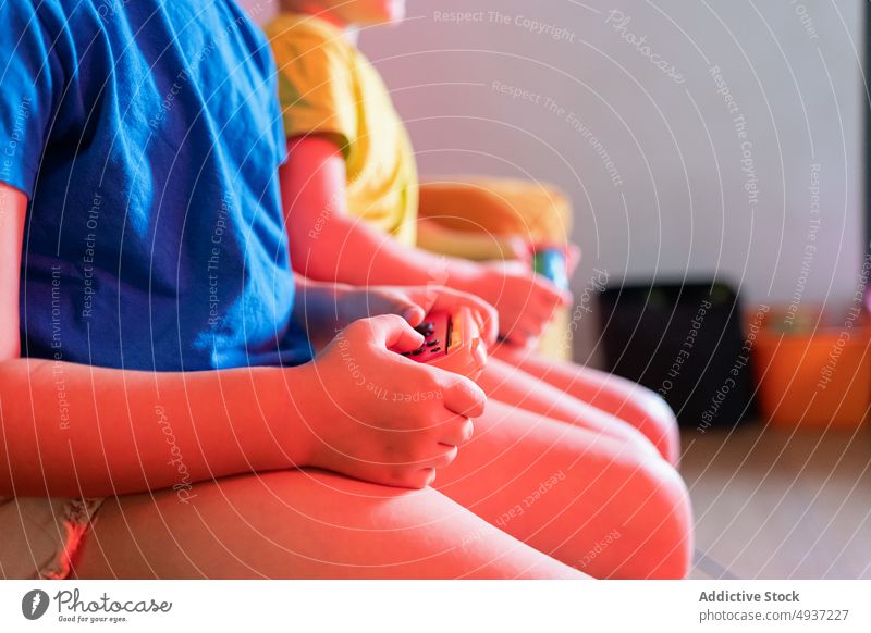 Anonyme Kinder spielen abends ein Videospiel Geschwisterkind Abend Wohnzimmer unterhalten Vergnügen Zeitvertreib Freizeit Liege Sofa halbdunkel neonfarbig spät