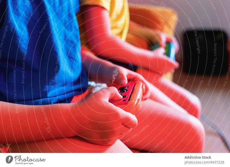 Anonyme Kinder spielen abends ein Videospiel Geschwisterkind Abend Wohnzimmer unterhalten Vergnügen Zeitvertreib Freizeit Liege Sofa halbdunkel neonfarbig spät