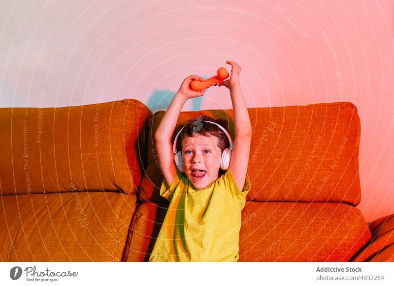 Fröhlicher Junge, der beim Spielen eines Videospiels seinen Sieg feiert Kind gewinnen spielen unterhalten Vergnügen Triumph Zeitvertreib Arme hochgezogen