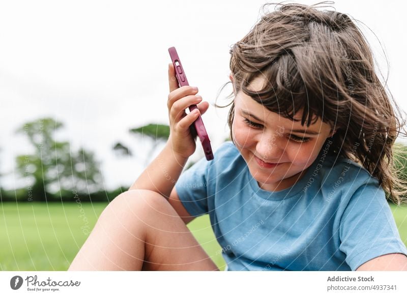 Glückliches Mädchen, das im Park mit seinem Smartphone spricht sprechen Rasen Sommer Wochenende heiter Barfuß Freude Telefonanruf reden froh Kommunizieren