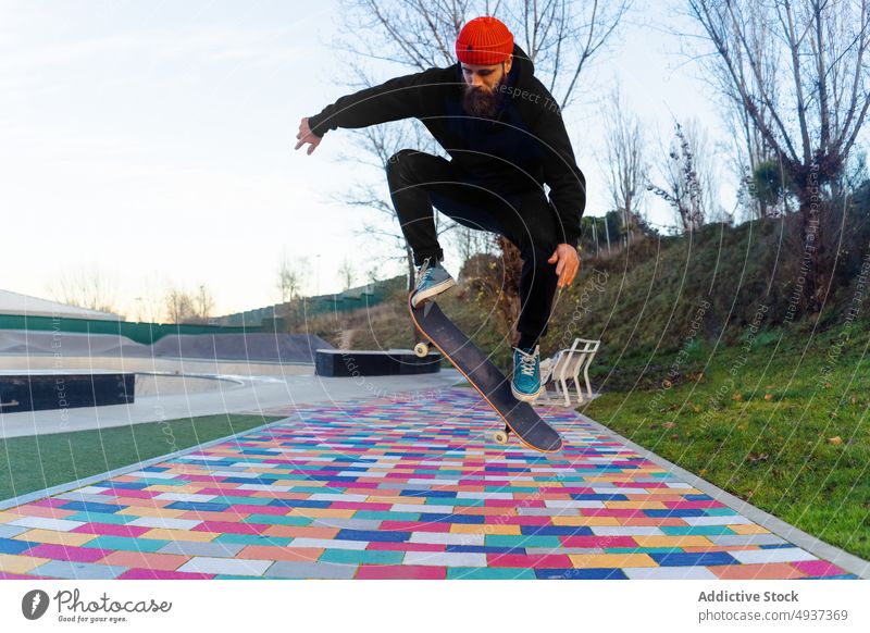 Mann springt mit Skateboard in Skatepark Skater springen Trick Stunt Skateplatz ausführen Hipster Hobby männlich über der Erde Energie Straßenbelag farbenfroh