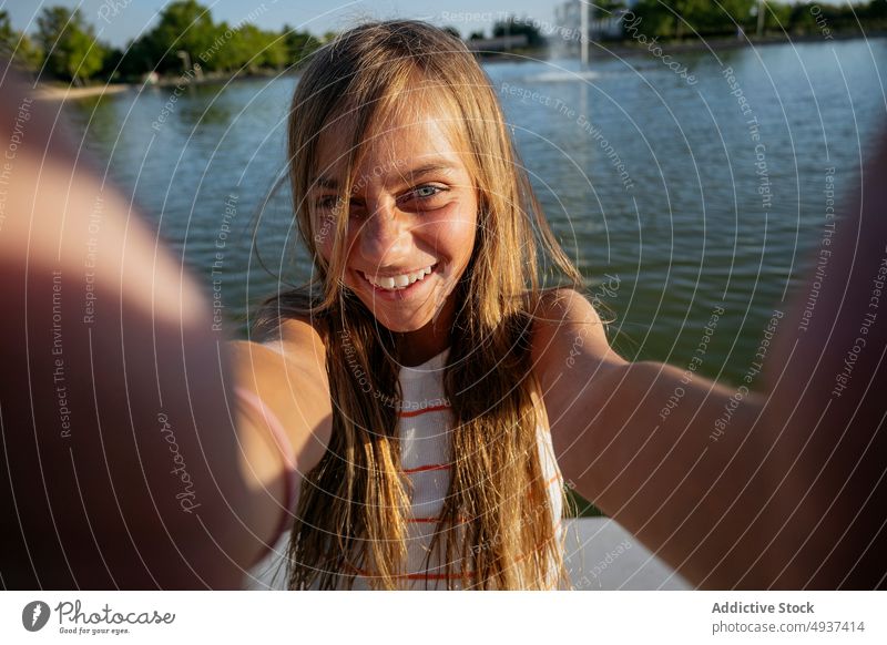Mädchen nimmt Selfie auf Böschung Kind Smartphone Lächeln Fotografie soziale Netzwerke Stauanlage Hafengebiet Wasser Fluss einfangen Gedächtnis Moment Inhalt