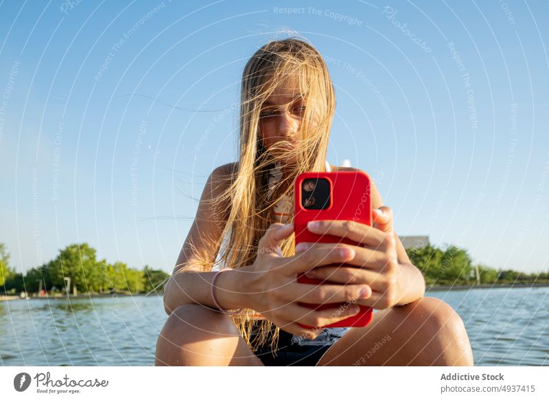 Mädchen surft auf Smartphone in der Nähe des Flusses Kind Textnachricht Browsen online Wasser Stauanlage Teenager Hafengebiet Talkrunde Strandpromenade Internet