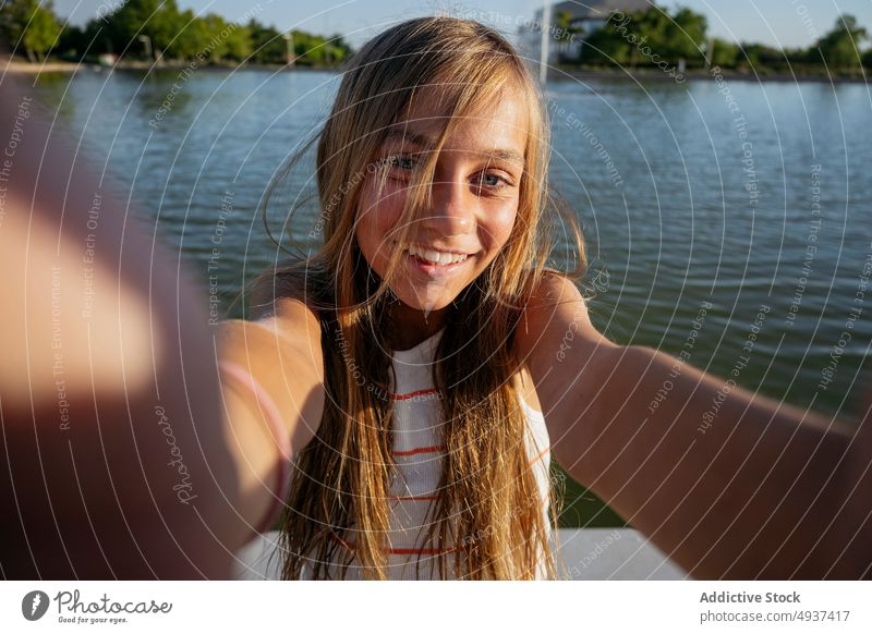 Mädchen nimmt Selfie auf Böschung Kind Smartphone Lächeln Fotografie soziale Netzwerke Stauanlage Hafengebiet Wasser Fluss einfangen Gedächtnis Moment Inhalt