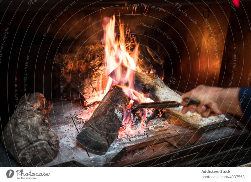 Gesichtslose Person, die brennendes Brennholz rührt Feuerstelle rühren Brandwunde Flamme gemütlich feurig brennbar heimwärts heiß Raum warm Licht erwärmen