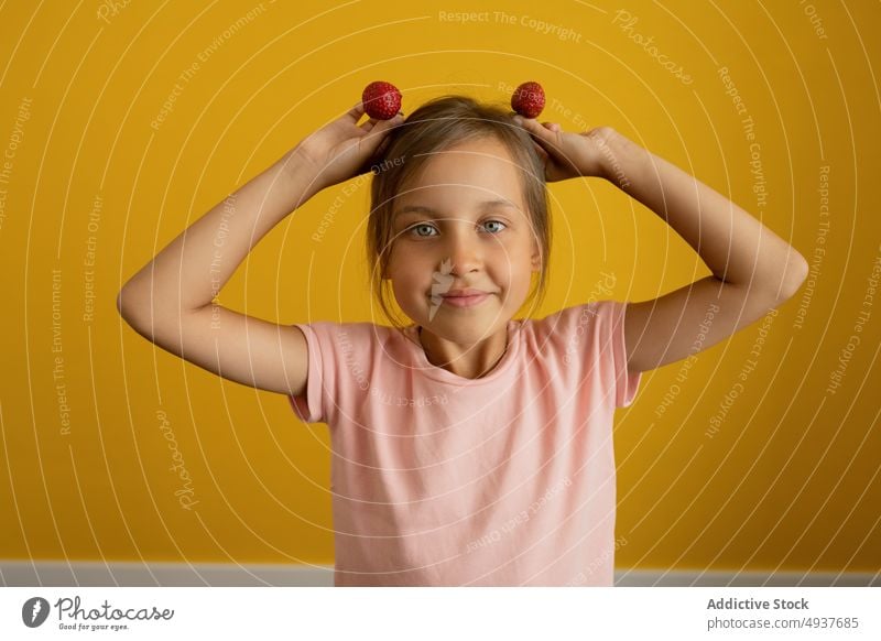 Mädchen macht Ohren aus Erdbeeren spielerisch reif farbenfroh lustig niedlich Porträt Kind hell Kindheit bezaubernd lässig organisch T-Shirt lebhaft süß