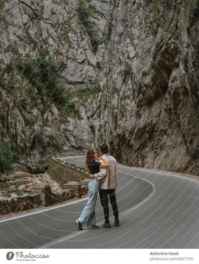 Romantisches junges Paar, das sich auf der Straße inmitten massiver Felsklippen umarmt Umarmung Berge u. Gebirge Ausflug Reisender Zusammensein Umarmen Liebe