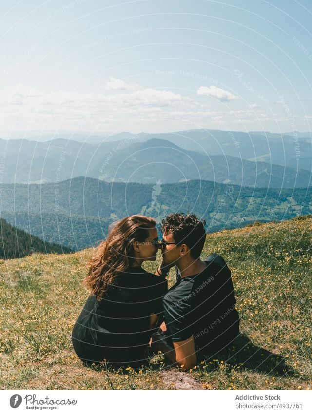 Verliebtes Paar umarmt sich auf einem grasbewachsenen Hügel in einem Gebirgstal Berge u. Gebirge Kuss Liebe Natur reisen Ausflug romantisch Zusammensein