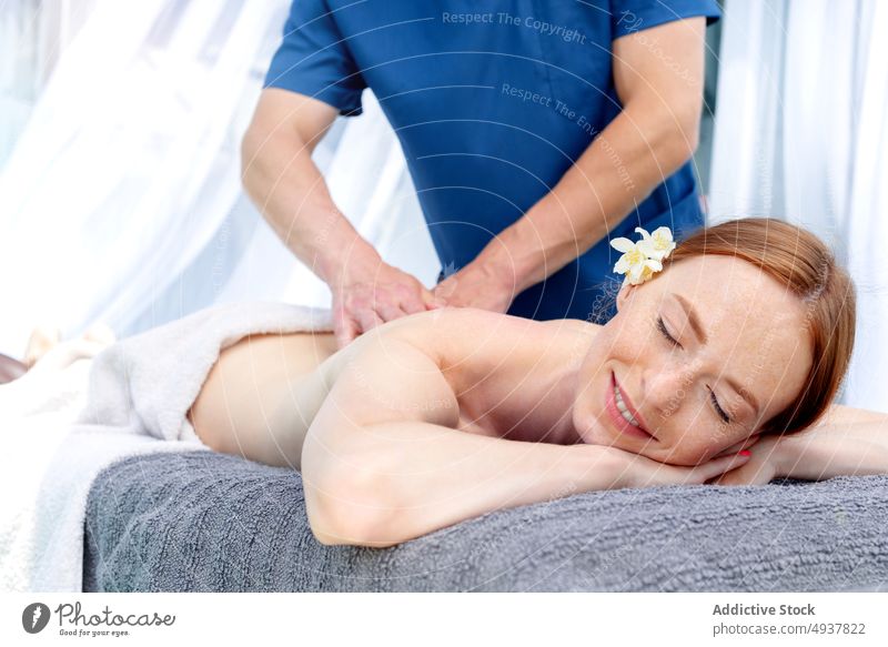 Frau lächelnd und mit geschlossenen Augen bei der Massage Klient rote Haare Masseur Spa Resort Wochenende Glück Lächeln Sitzung Verfahren Mann Wellness
