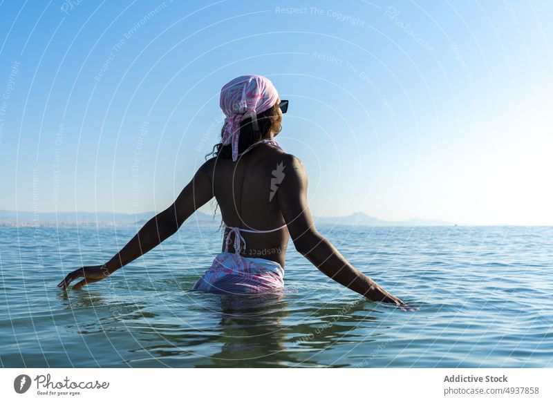 Schwarze Frau im Meerwasser stehend Wasser MEER Resort Urlaub Badeanzug Sommer Blauer Himmel Kopftuch Morgen schwarz Afroamerikaner ethnisch Badebekleidung