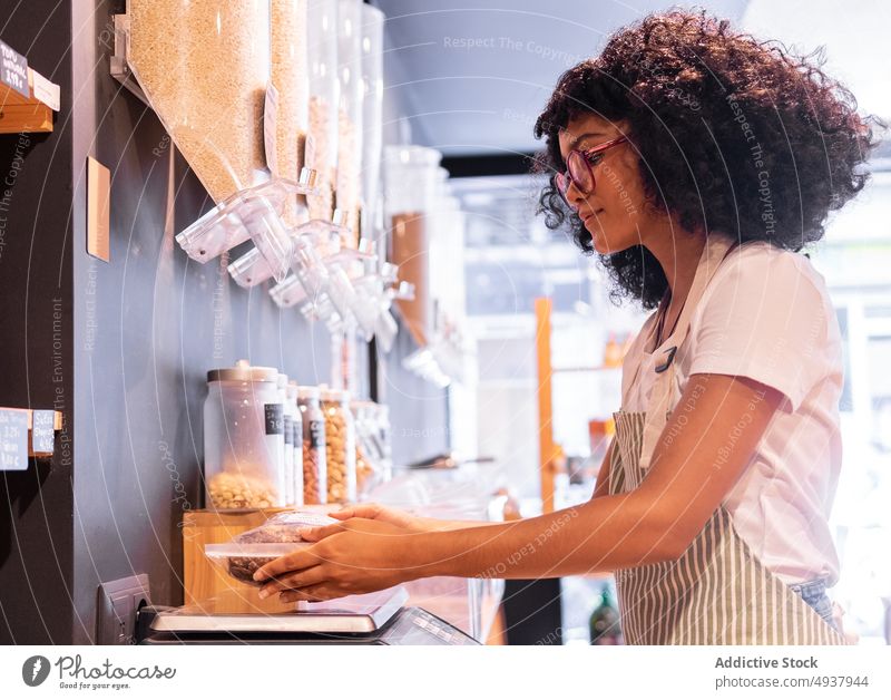 Ethnische Verkäuferin wiegt Schokoladen-Cornflakes Frau wiegen Werkstatt Anbieter digital Gleichgewicht umweltfreundlich jung ethnisch schwarz Afroamerikaner