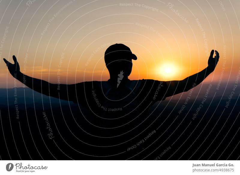 Sonnenuntergang mit der Silhouette eines jungen Mannes in einer Haltung der Dankbarkeit gegenüber der Sonne Tribut geistig Versand Herrlichkeit Fülle Angebot