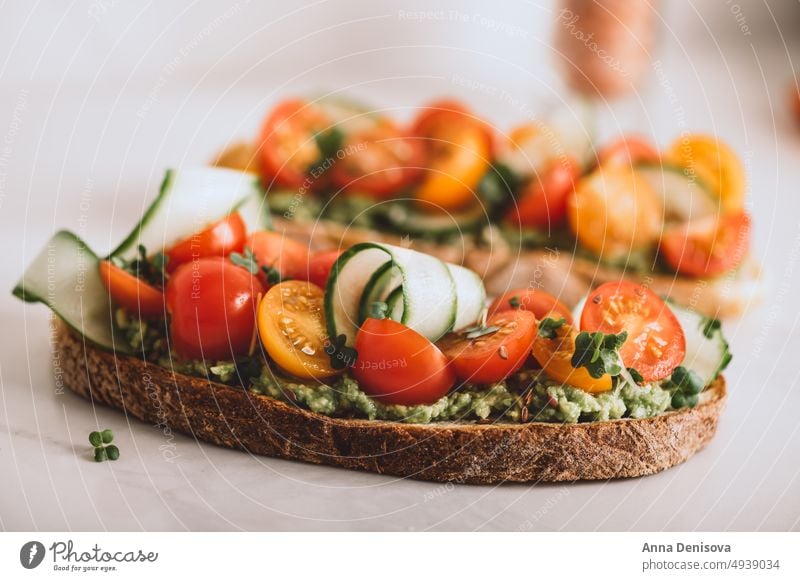 Toast mit Kirschtomaten und Avocado Zuprosten gestampft cucucmber Avocado-Toast Brot Mikro-Grün Mittagessen Frühstück frisch Lebensmittel Vegetarier Gesundheit