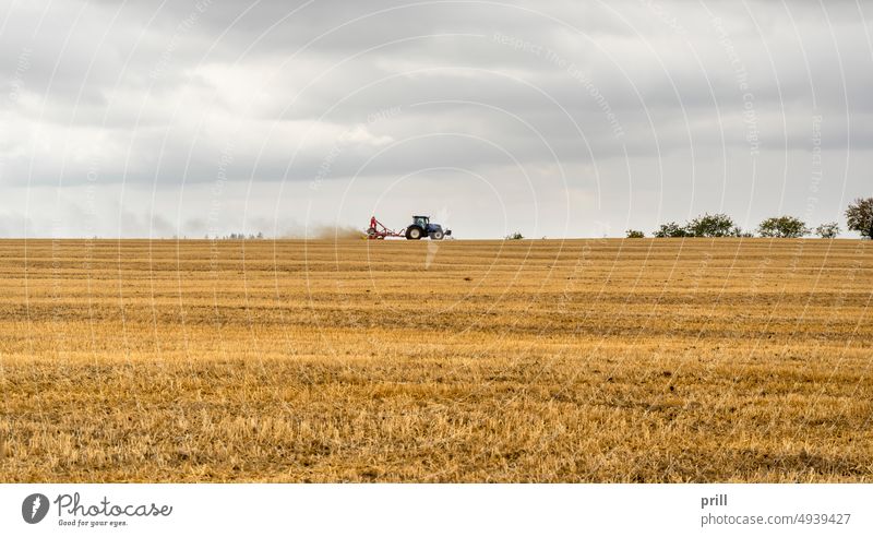 Traktor auf einem Stoppelfeld Traktionsmotor Ackerbau ländlich Feld Landwirtschaft Ackerland kultivierend Sommer stürmisch getrübt bedeckt Schonung Hohenlohe