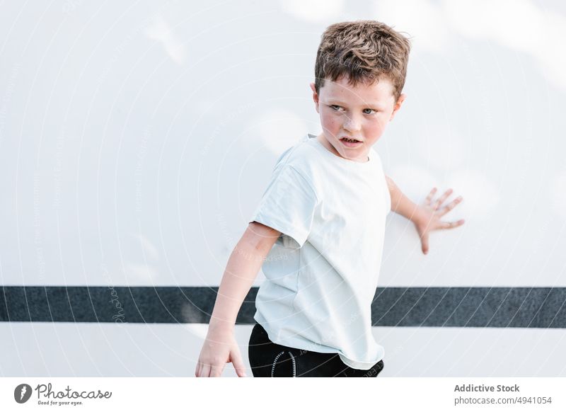Junge steht vor weißer Wand Straße sonnenbeschienen Wochenende Vorschein tagsüber Sommer urban modern Kind lässig Sonnenlicht Tageslicht Streifen Gebäude