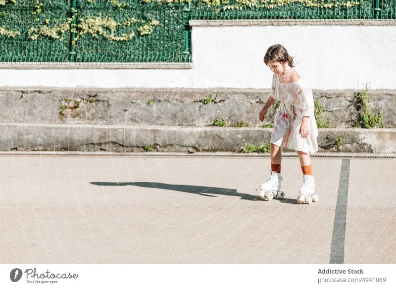 Konzentriertes Mädchen auf Rollschuhen auf der Straße Mitfahrgelegenheit Rollerskate Sommer Wochenende Aktivität Hobby urban Kind Zeitvertreib lässig Fokus