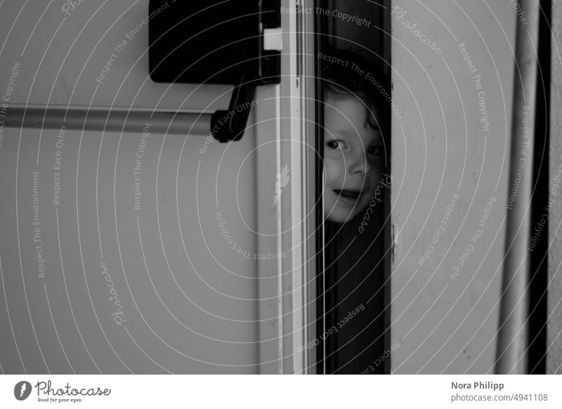 Verstecke spielen verstecken Junge Kind Freude Blick Gesicht Blick in die Kamera Kindheit Mensch Kleinkind 1-3 Jahre Porträt Schwarzweißfoto Tür öffnen niedlich