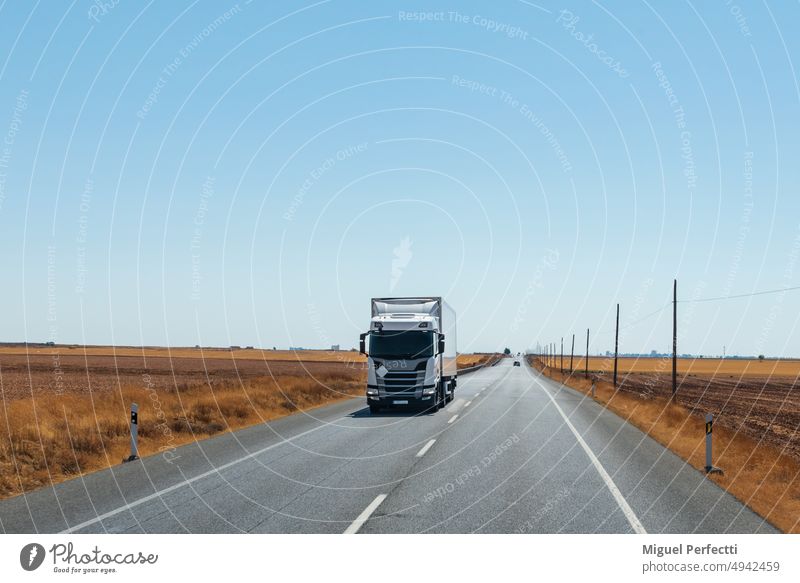 Kühltransporter auf einer geraden Straße, mit flachem Horizont und klarem Himmel. Lastwagen Transport Fracht Natur Perspektive Verkehr Anhänger Landschaft