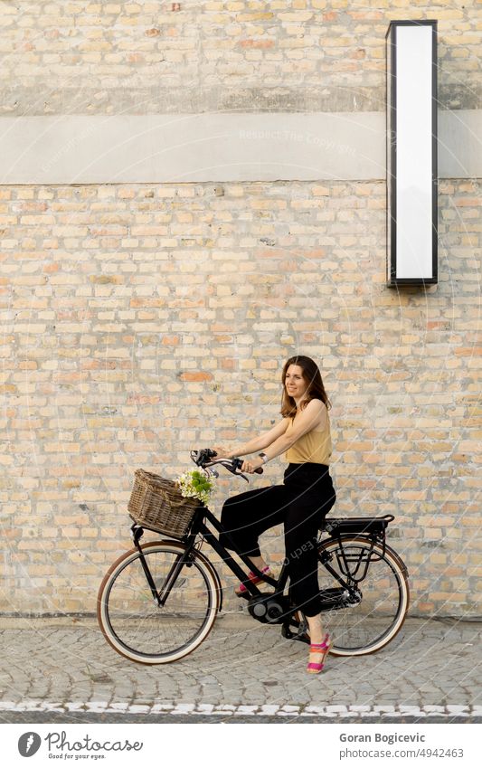 Frau mit Blumen im Korb eines Elektrofahrrads Lifestyle im Freien Reiten Großstadt Straße urban Verkehr Aktivität Erwachsener schön Fahrrad blanko Kaukasier