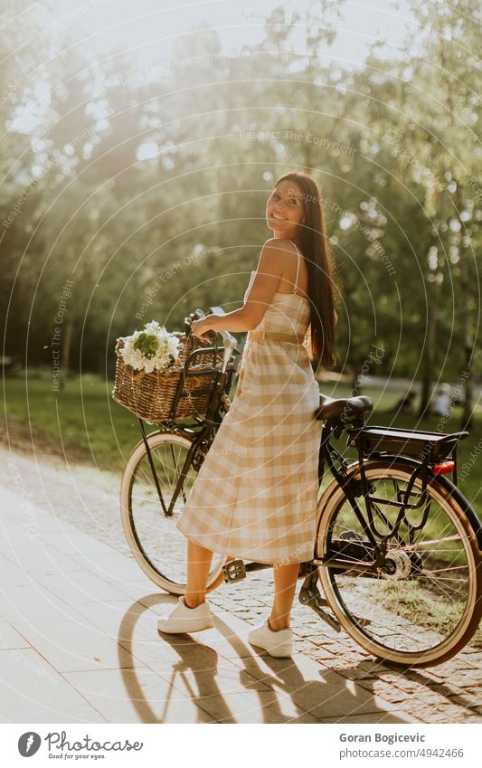 Junge Frau mit Blumen im Korb eines Elektrofahrrads aktiv Aktivität Erwachsener schön Fahrrad Kaukasier Fahrradfahren Tag ebike Übung Blumenkorb Freizeit