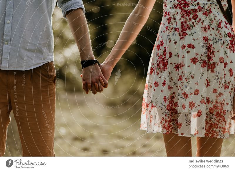 Ein verliebtes Paar steht nebeneinander und hält sich an den Händen. Mann und Frau tragen Sommerkleid und Kleidung. Verabredung im Freien. Trendy modische Kleidung.