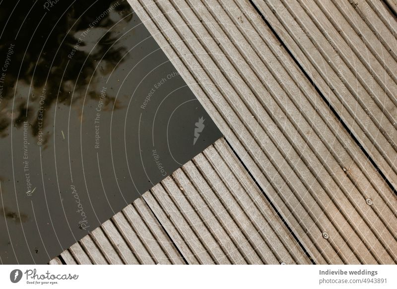 Ein hölzernes Deck Detail über einem Teich. Abstrakte architektonische Muster Detail einer Holzterrasse im Park. Modernes Minimal-Konzept, Raum kopieren. Parallele Linien.