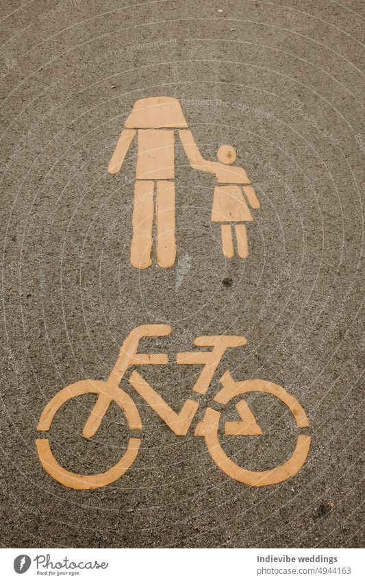 Ein Radwegschild und ein Fußgängerwegschild auf dem Asphalt. Gelbe Farbe, schwarze Straße. Der Kopf des Fußgängers fehlt. Städtische Straßenmarkierung. Fahrrad