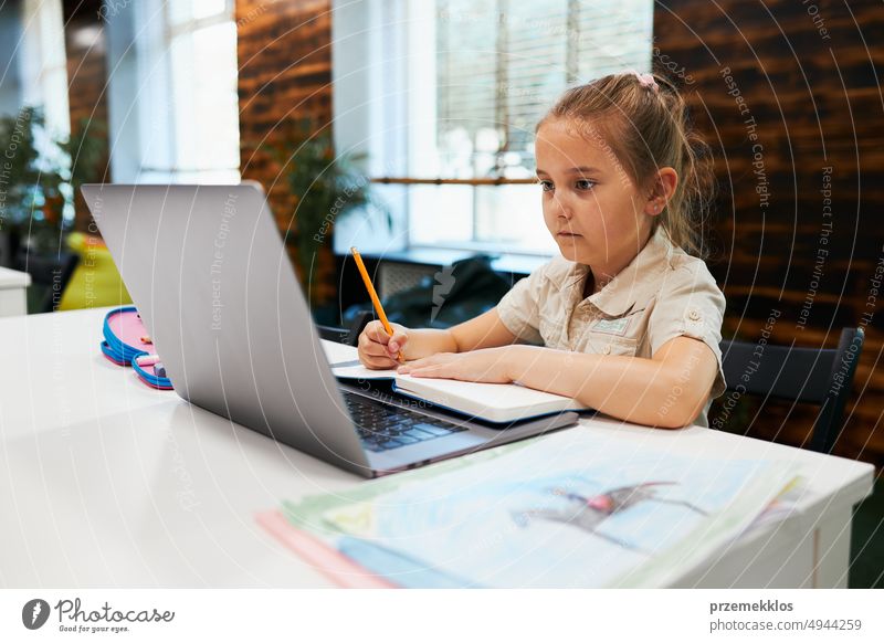 Engagierte, absorbierte Schülerin macht ihre Hausaufgaben mit dem Laptop im After School Club in der Grundschule. Zurück zur Schule. Kind nutzt Technologie im Informatikunterricht. Kluges Mädchen lernt von Bildungsanwendung in der Schule