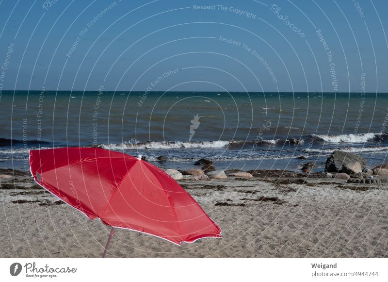 Roter Sonnenschirm am Strand der Ostsee Nordsee Norddeutschland Schleswig-Holstein Sandstrand Kiesel Steine Sommer Meer Entspannung Urlaub Ruhe Auszeit genießen