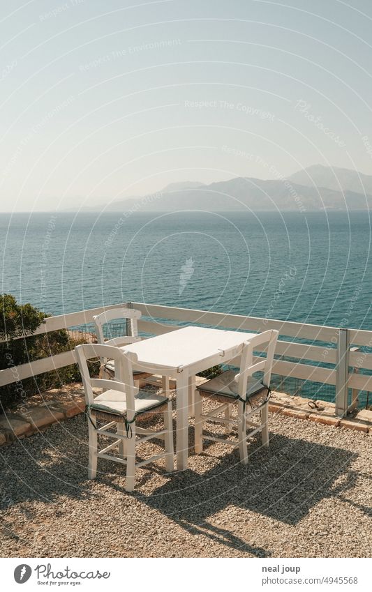 Tisch- und Stuhlgarnitur in griechischem Restaurant mit weitem Blick über das Meer auf die Berge Außenaufnahme Terrasse Tisch und Stühle Griechenland
