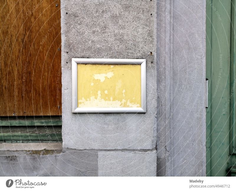 Verwahrlostes Schild mit gelbem Hintergrund und silbernem Rahmen auf grauem Beton in den Gassen der Altstadt von Brügge in Westflandern in Belgien wand fenster