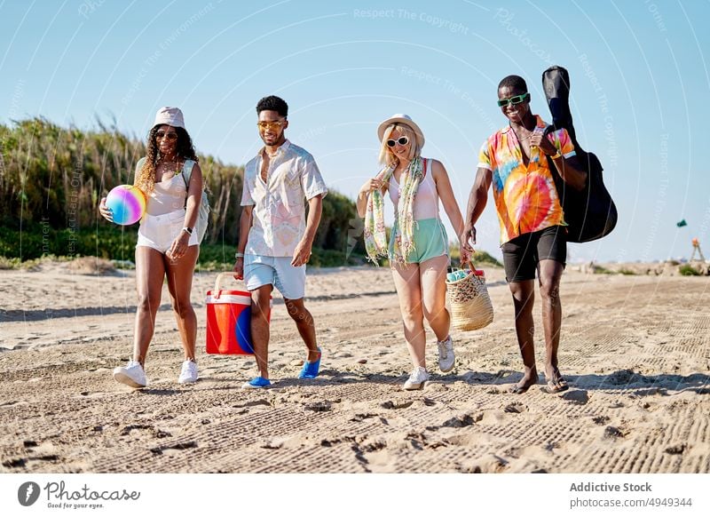 Glückliche Freunde am Strand Spaziergang Lächeln Sommer Wochenende Zusammensein Sand Blauer Himmel Resort tagsüber Männer froh Frauen jung Freude schlendern