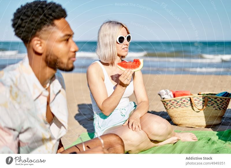 Verschiedene Freunde essen Obst und hören einem Gitarristen zu spielen Gitarre Strand zuhören Lächeln Frucht MEER Sommer Männer Frauen Wochenende Picknick Glück