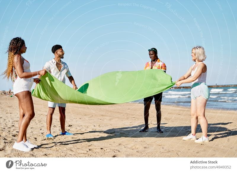 Verschiedene Männer und Frauen legen eine Decke am Strand aus Freund MEER Wochenende Sommer winken Aufstrich Zusammensein Freundin Partnerschaft Urlaub Küste