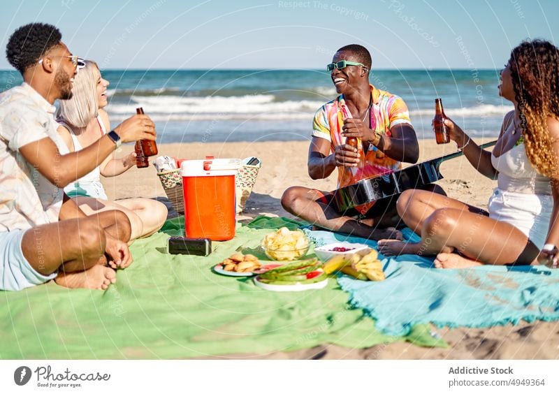 Verschiedene Freunde trinken Bier und essen Obst Strand Picknick Lächeln Klirren Flasche Glück Wochenende Männer Frauen Sommer jung vielfältig