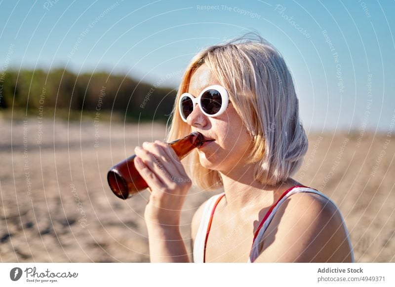 Junge Frau trinkt Bier am Strand trinken Wochenende Sommer Flasche Alkohol Picknick schlürfen jung blond Urlaub Sonnenbrille Getränk Feiertag Durst Sonnenlicht