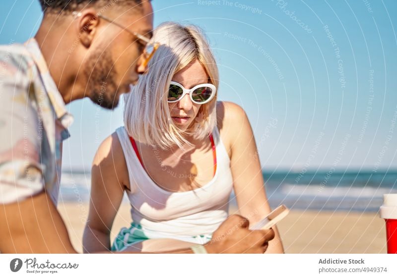 Verschiedene Freunde benutzen Smartphone am Strand benutzend teilen MEER Zusammensein Nachrichten blättern Wochenende Mann Frau Sommer jung vielfältig