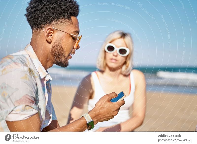 Verschiedene Freunde benutzen Smartphone am Strand benutzend teilen MEER Zusammensein Nachrichten blättern Wochenende Mann Frau Sommer jung vielfältig